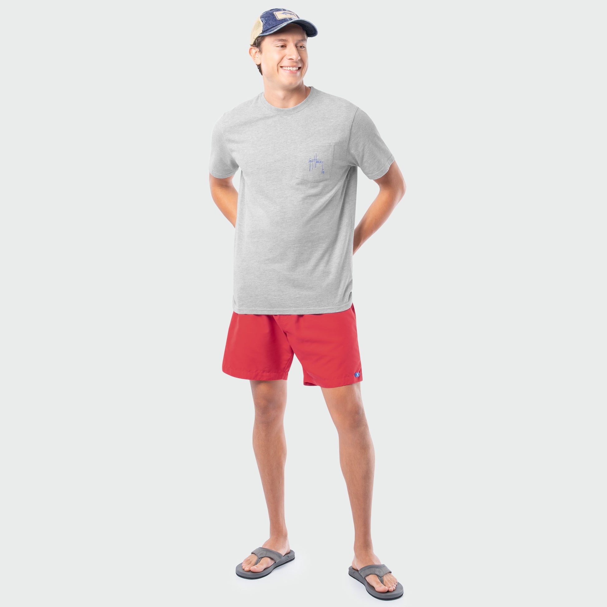 Man wearing a gray t-shirt and red shorts on a white background