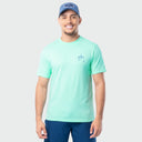 Man wearing a light green Guy Harvey t-shirt and blue cap on a white background