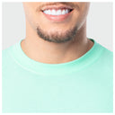 Close-up of a person wearing a light green shirt with a plain background