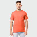 Man wearing an orange t-shirt with a small logo on a light gray background