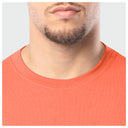 Close-up of a person wearing an orange shirt with a neutral background