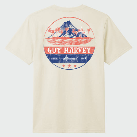 Flat lay of a Guy Harvey t-shirt with a volcano graphic on a plain background