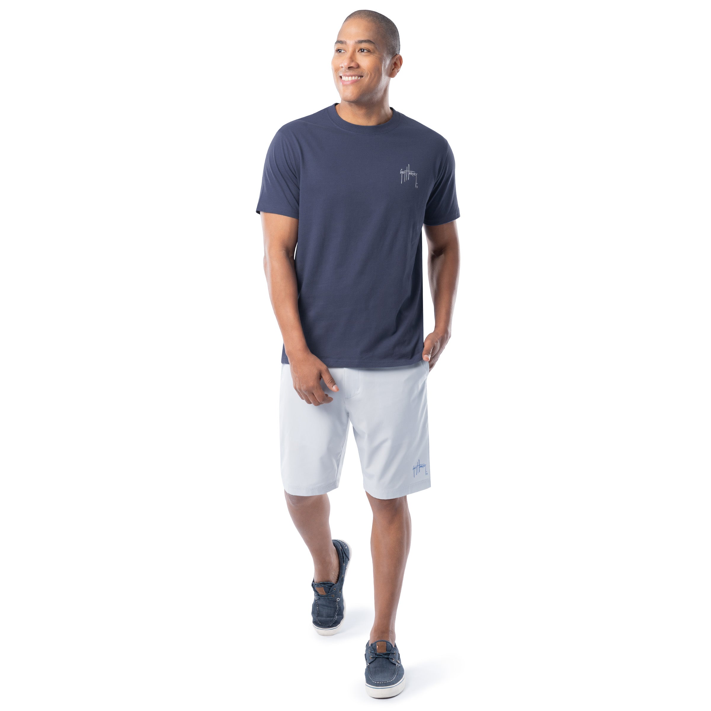 Man wearing a navy t-shirt and white shorts on a white background