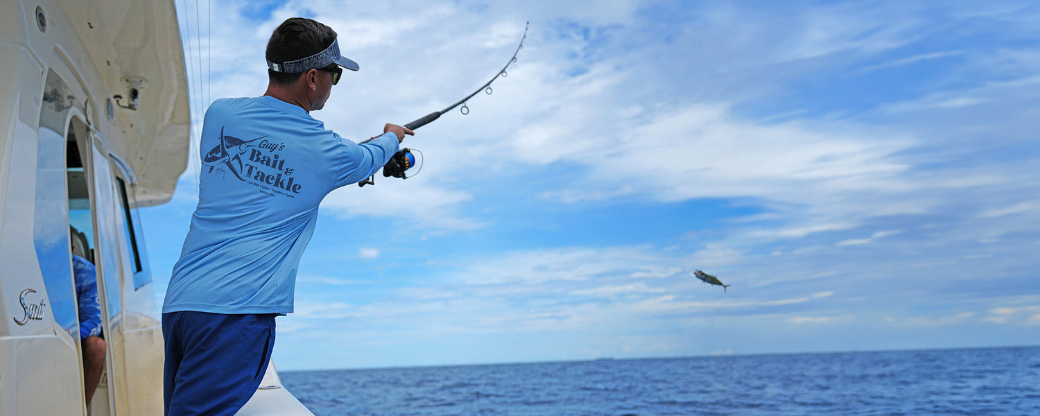 A man wearing a Guy Harvey Eco Cast sun protection fishing shirt on a boat while fishing.