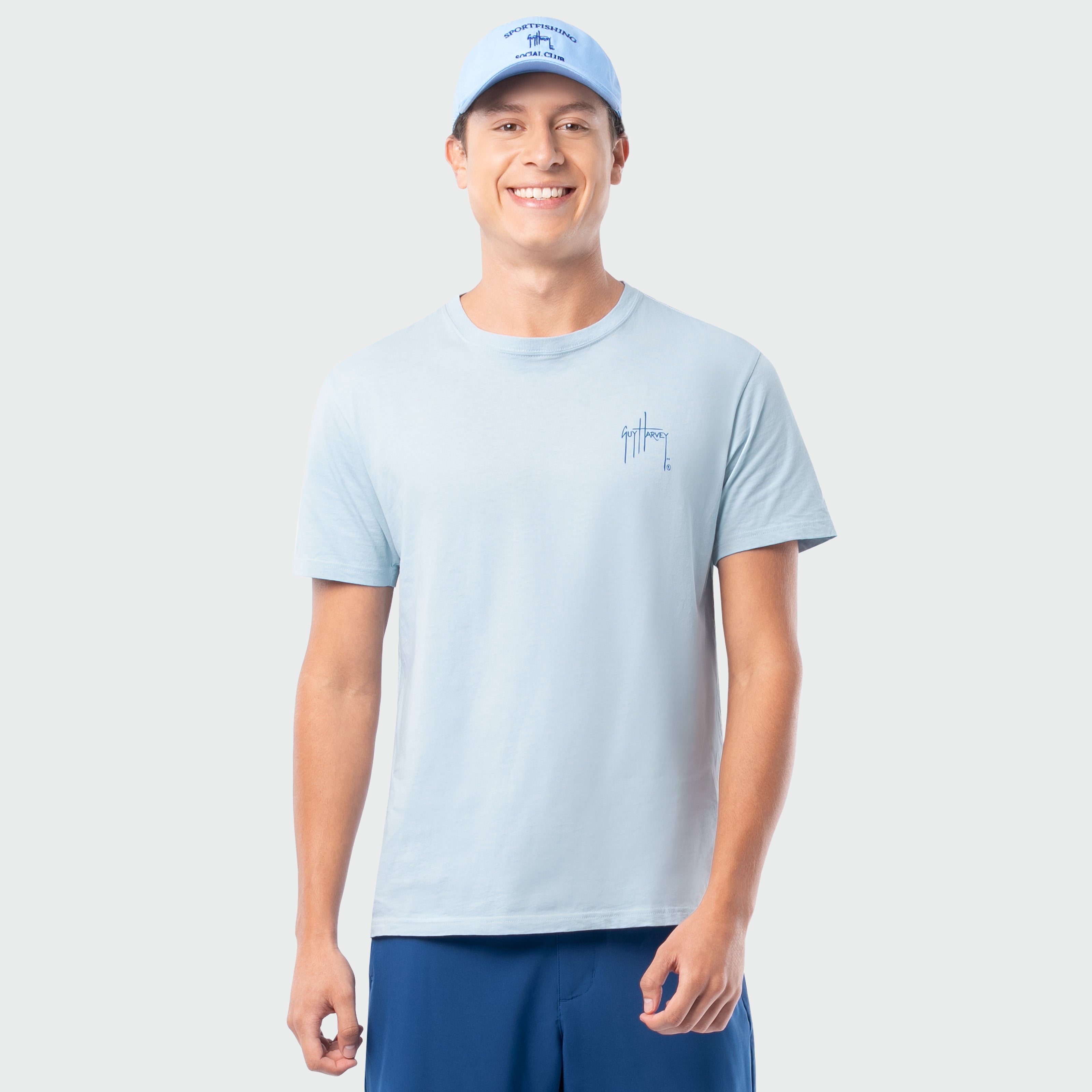 Man wearing a light blue t-shirt and cap on a plain background