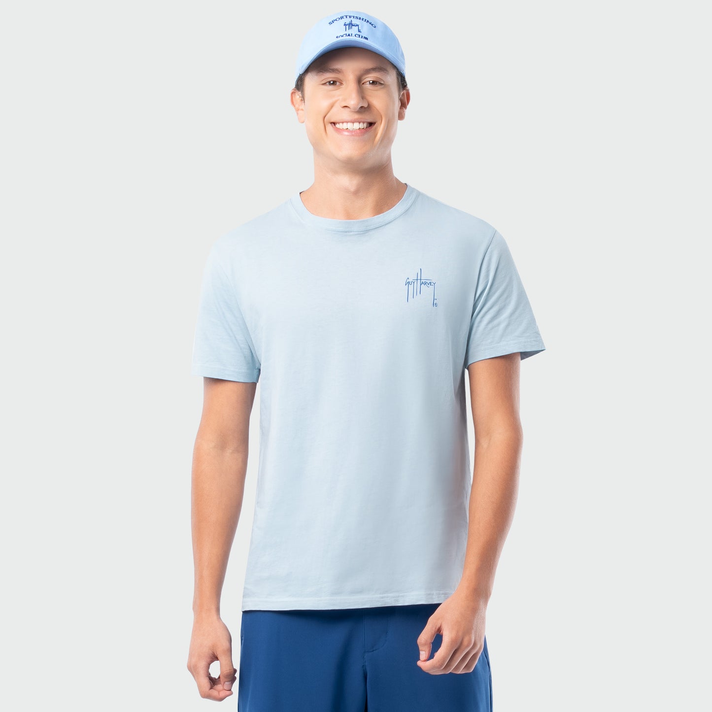 Man wearing a light blue t-shirt and cap on a plain background