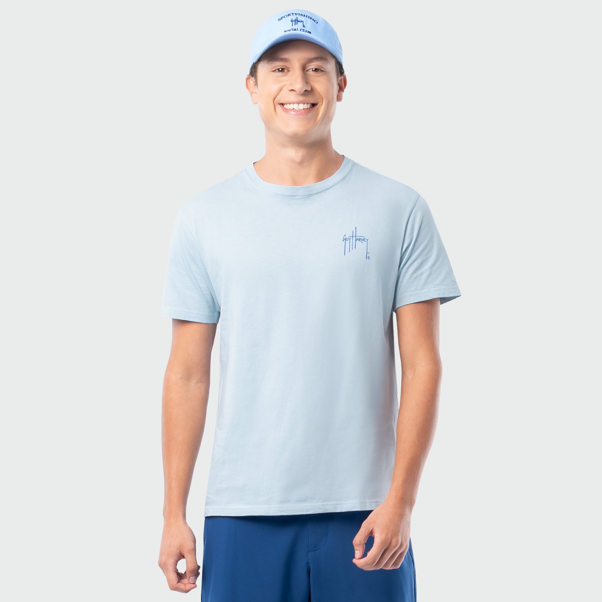 Man wearing a light blue t-shirt and cap on a plain background