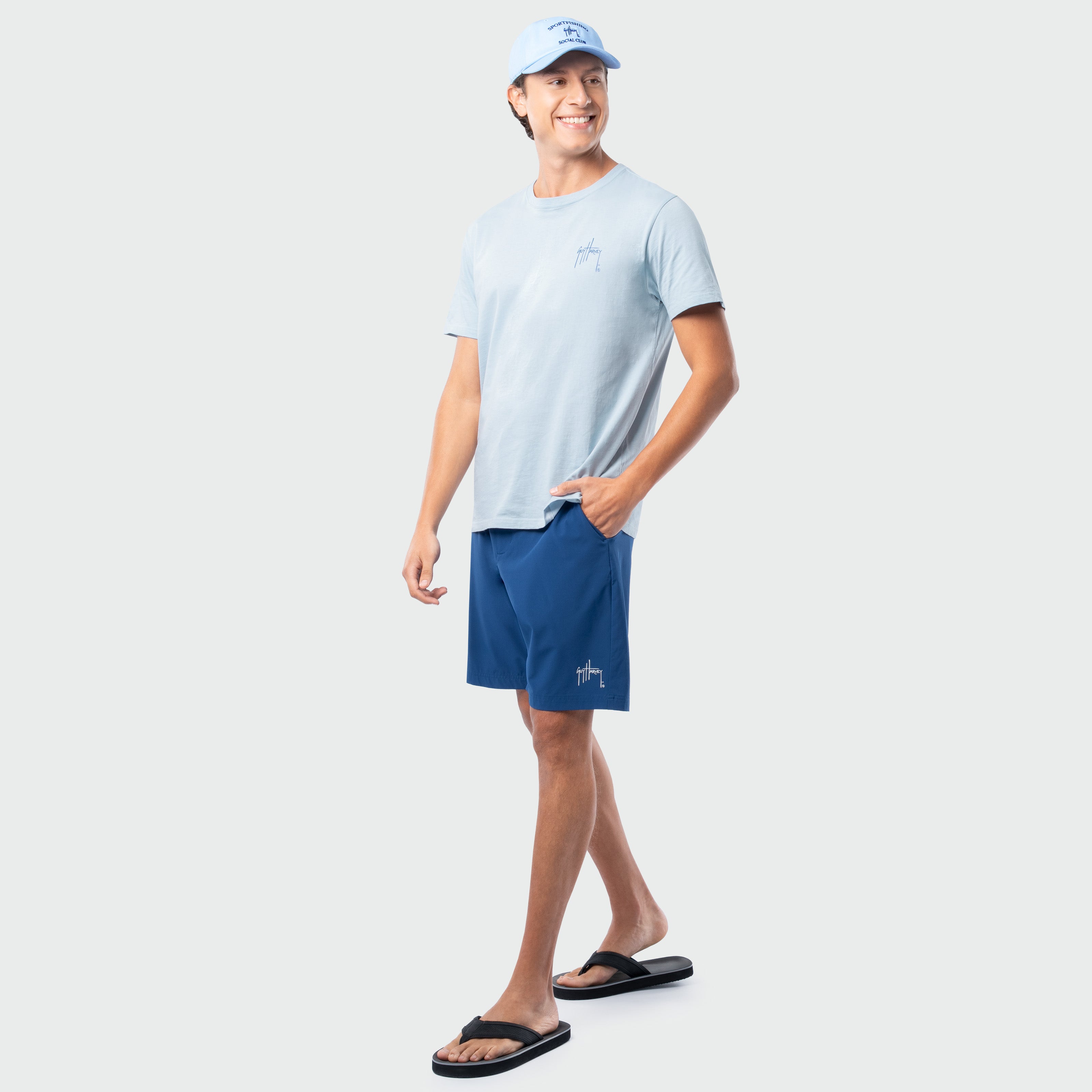 Man wearing a light blue t-shirt and navy shorts on a white background