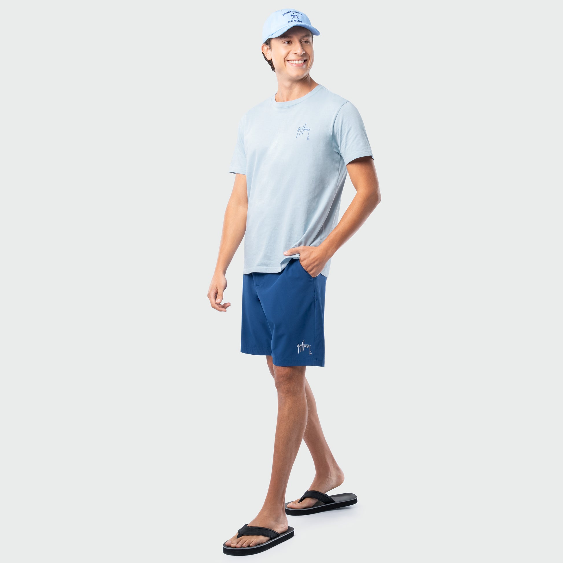 Man wearing a light blue t-shirt and navy shorts on a white background