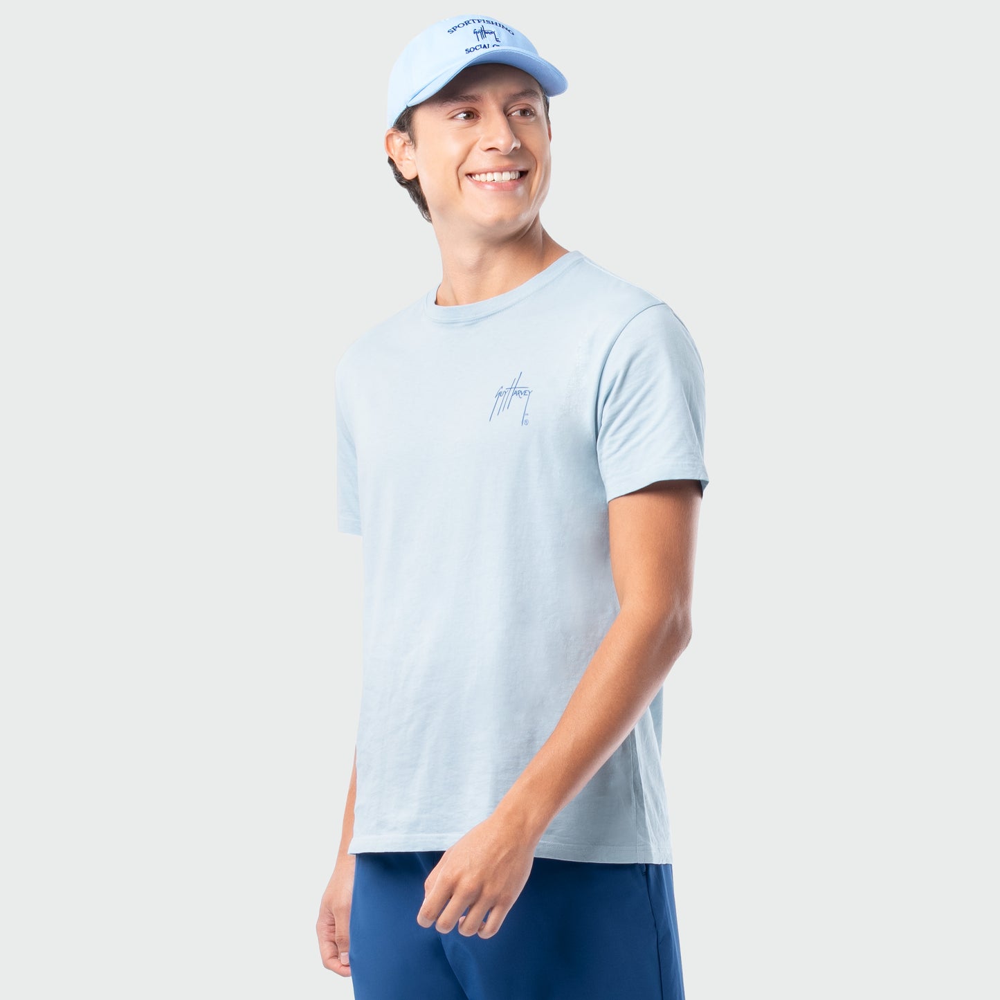 Person wearing a light blue t-shirt and cap on a plain background