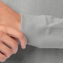 Close-up of a person's hand adjusting the ribbed cuff of a light gray long-sleeve shirt.
