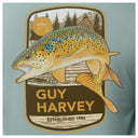 T-shirt with Guy Harvey logo featuring a  brown trout fish and forest design on a light blue background