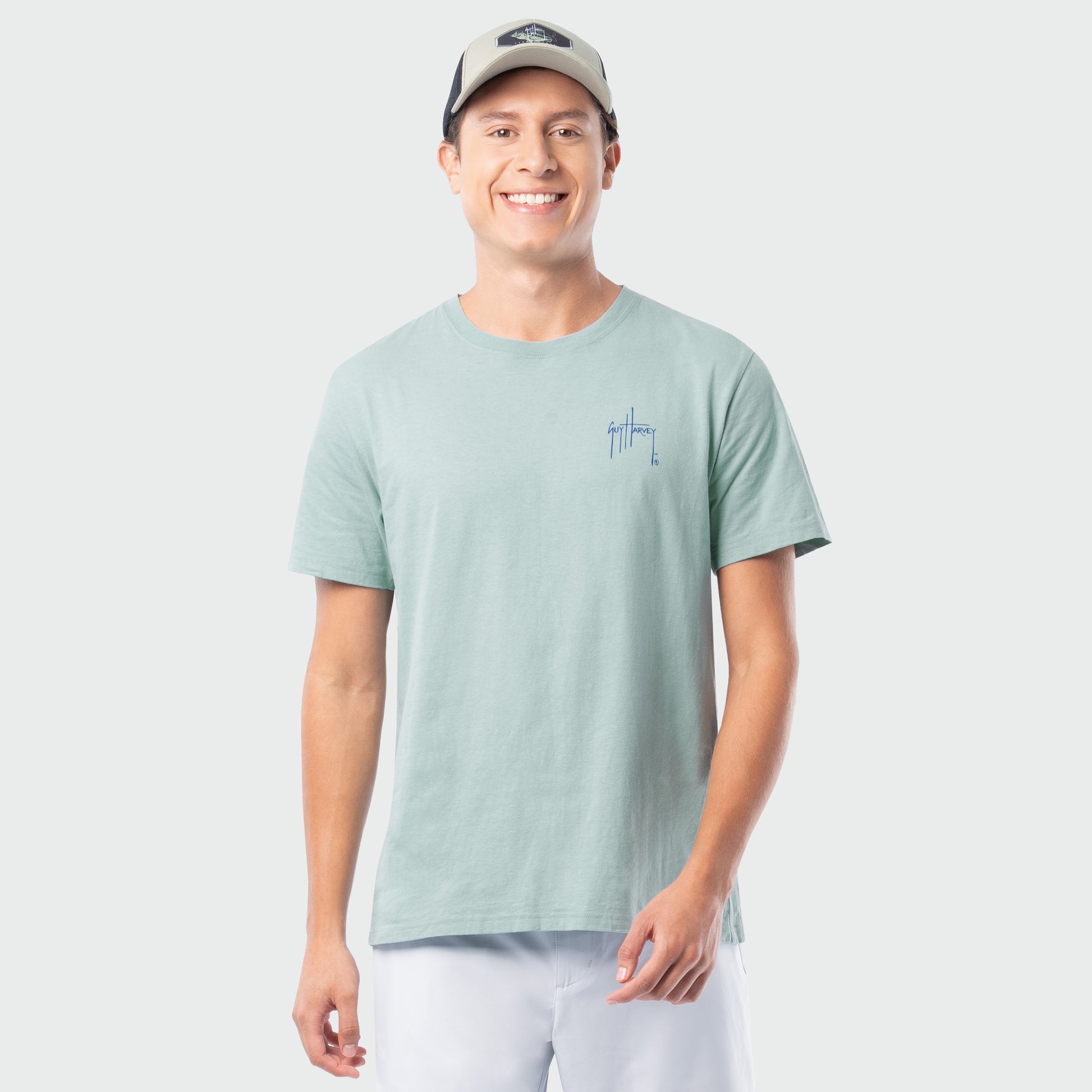 Man wearing a light green t-shirt with a small Guy Harvey logo on a white background