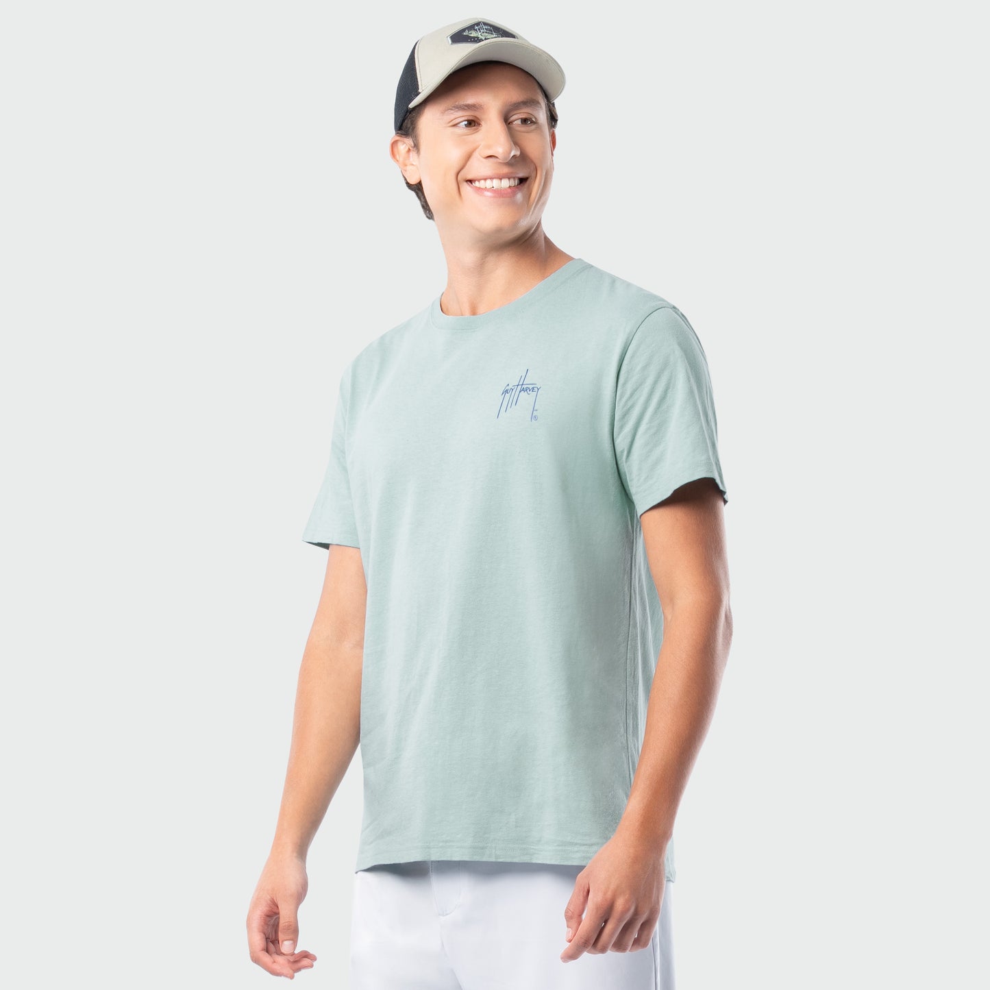 Man wearing a light green t-shirt with a logo on a white background