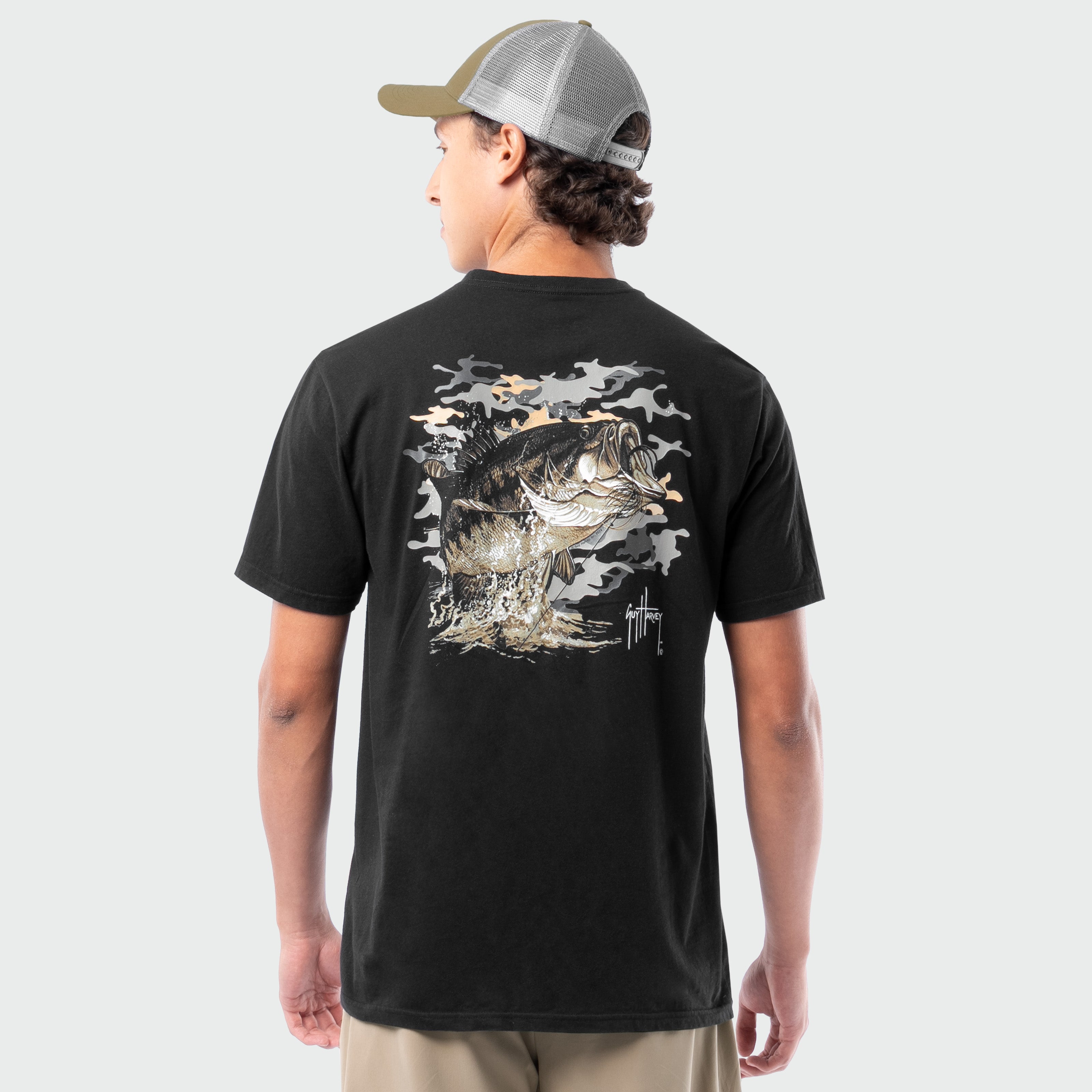 Person wearing a black t-shirt with a bass graphic on the back, standing against a plain background