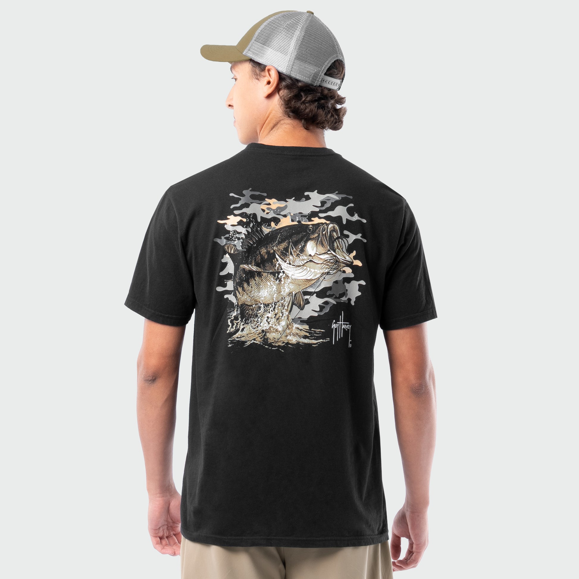 Person wearing a black t-shirt with a bass graphic on the back, standing against a plain background