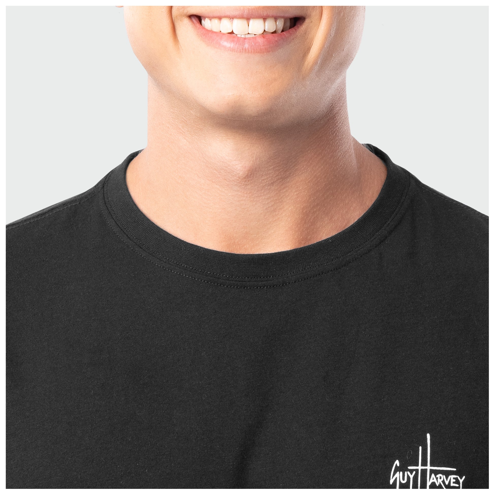 Close-up of a person wearing a black t-shirt with a visible brand logo on a plain background