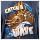 Close-up of a navy blue graphic t-shirt featuring a large brown stingray, striped fish, and bold text reading 'CATCH A WAVE' in white with orange outlines.