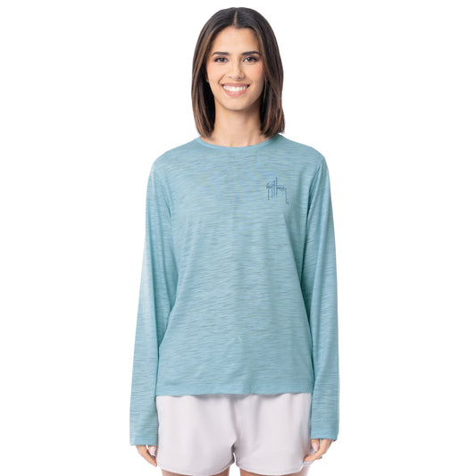 Woman wearing a light blue long-sleeve shirt with a small logo on a white background