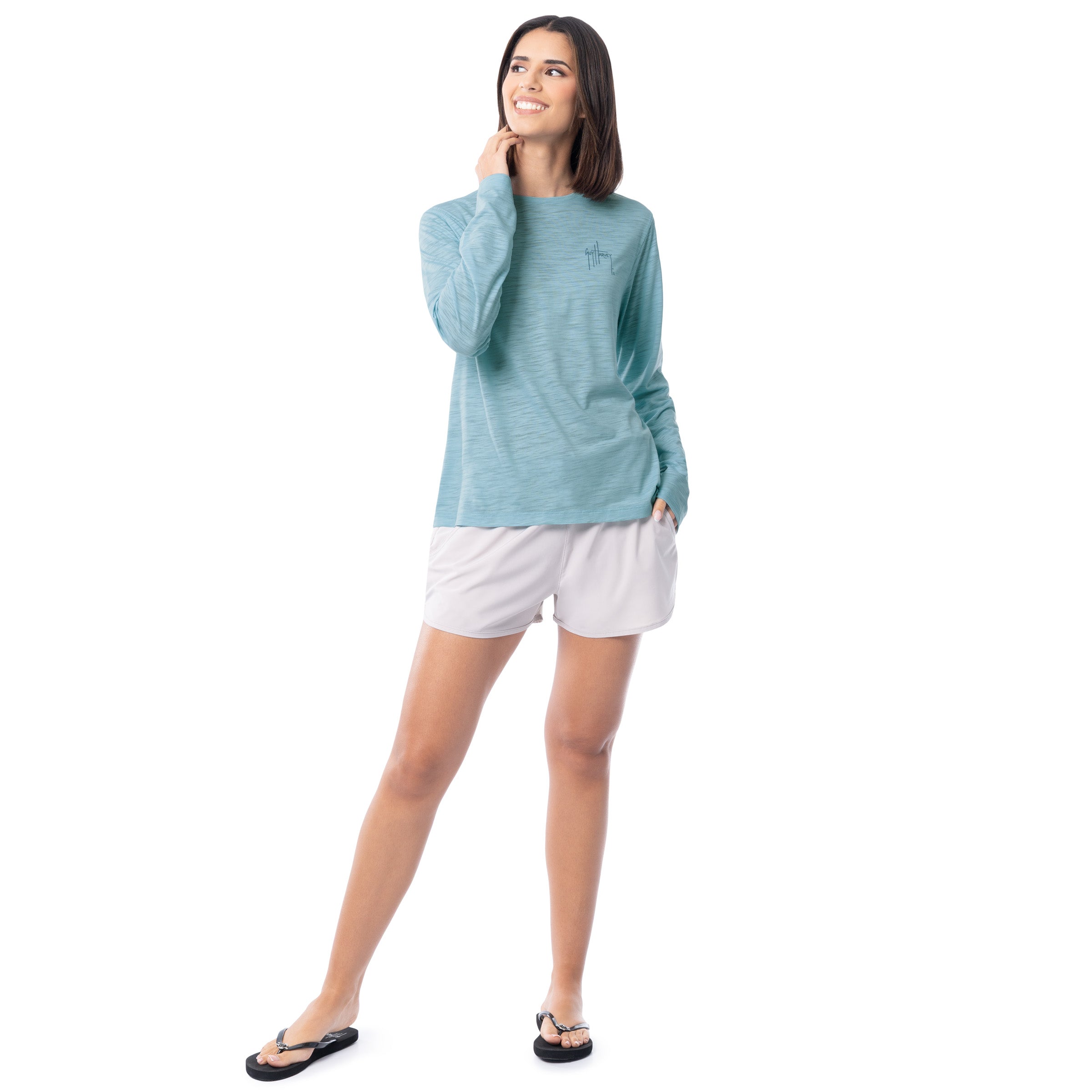 Woman wearing a light blue long-sleeve shirt and white shorts on a white background