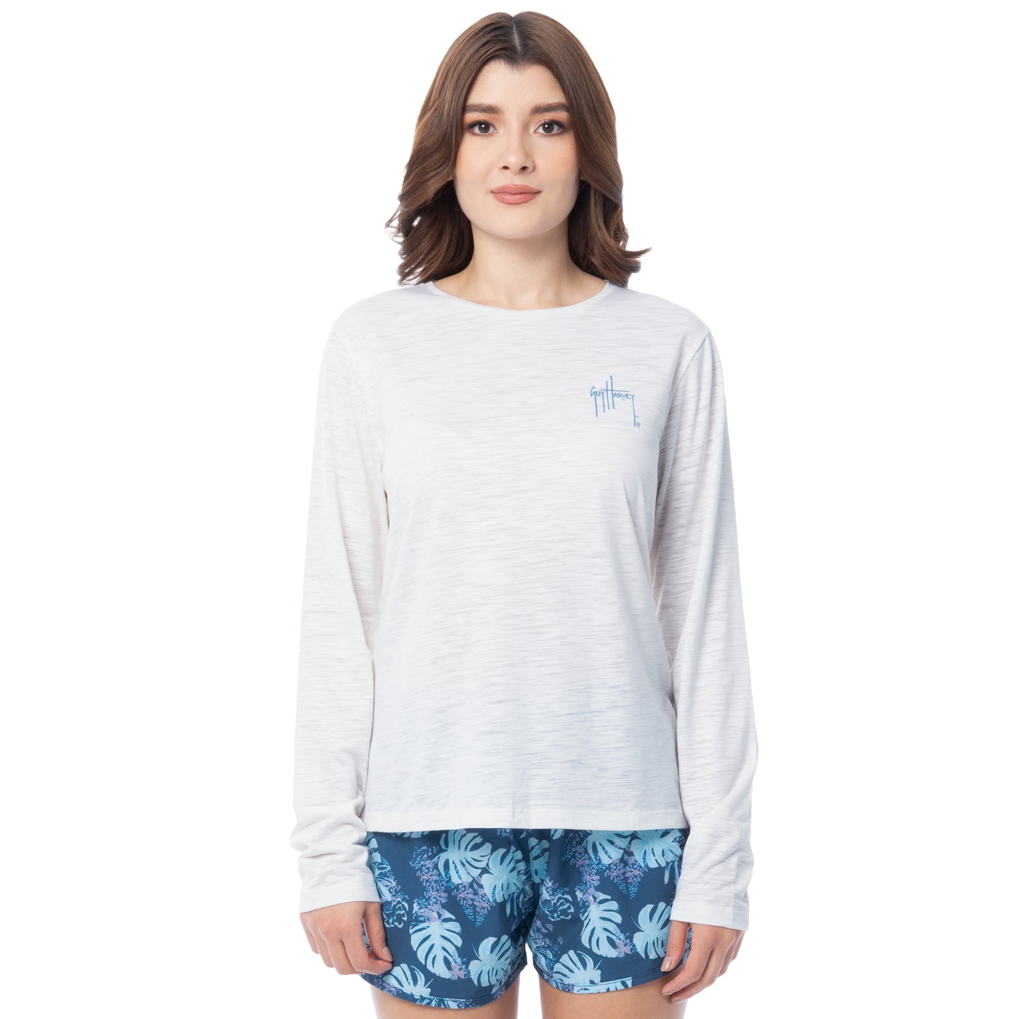 Woman wearing a white long-sleeve shirt and blue floral shorts on a white background