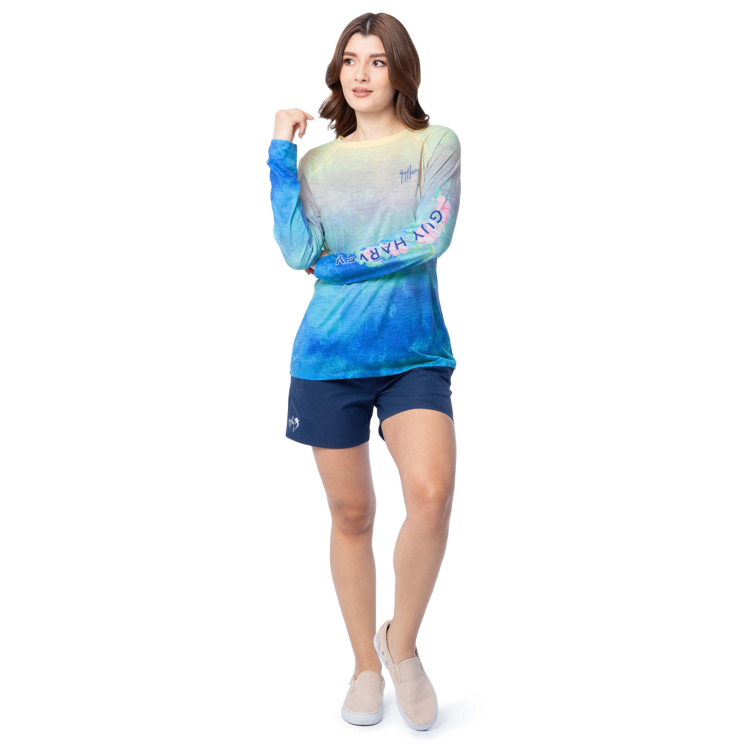 Woman wearing a colorful long-sleeve shirt and navy shorts on a white background