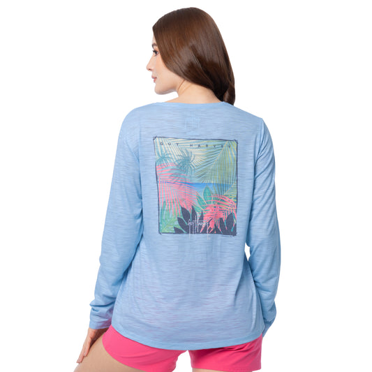 Woman wearing a blue long-sleeve shirt with a colorful palm tree design on the back, on a white background.