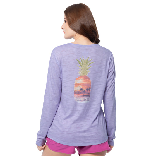 Woman wearing a purple long-sleeve shirt with a pineapple design on the back, standing against a white background.