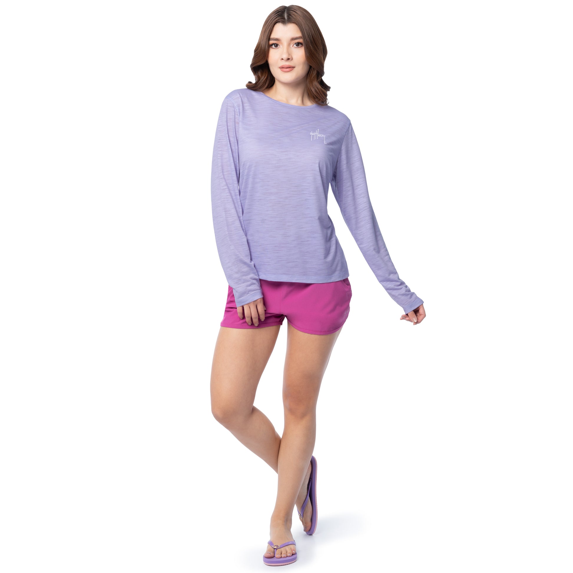 Woman wearing a purple long-sleeve shirt and pink shorts on a white background