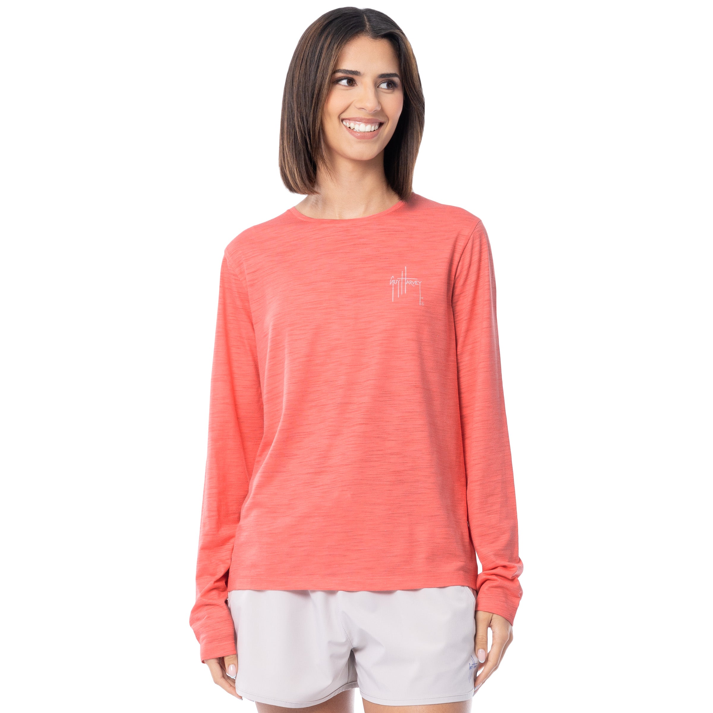 Woman wearing a coral long-sleeve shirt with a small Guy Harvey logo on a white background