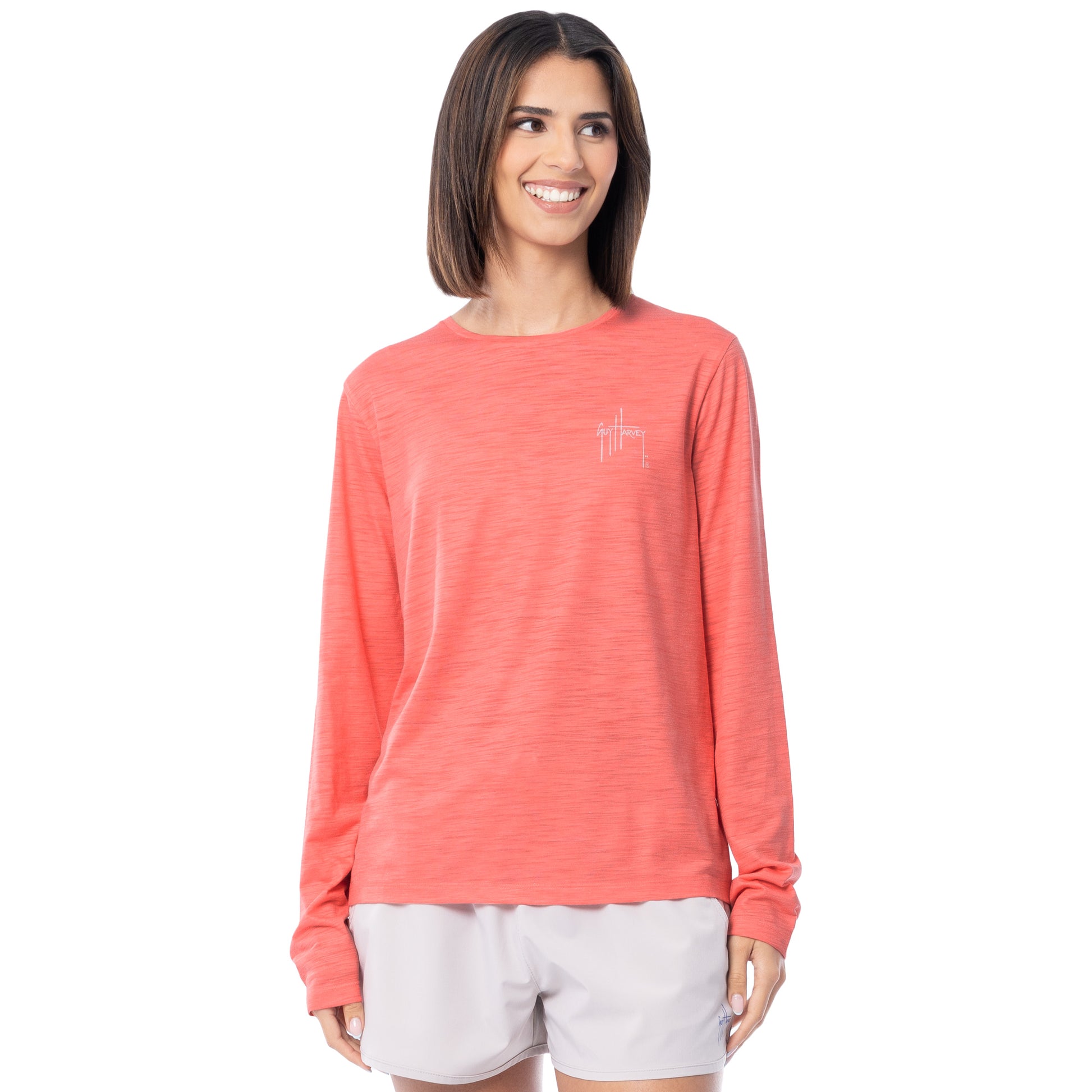 Woman wearing a coral long-sleeve shirt with a small Guy Harvey logo on a white background