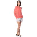 Woman wearing a coral long-sleeve top and white shorts on a white background
