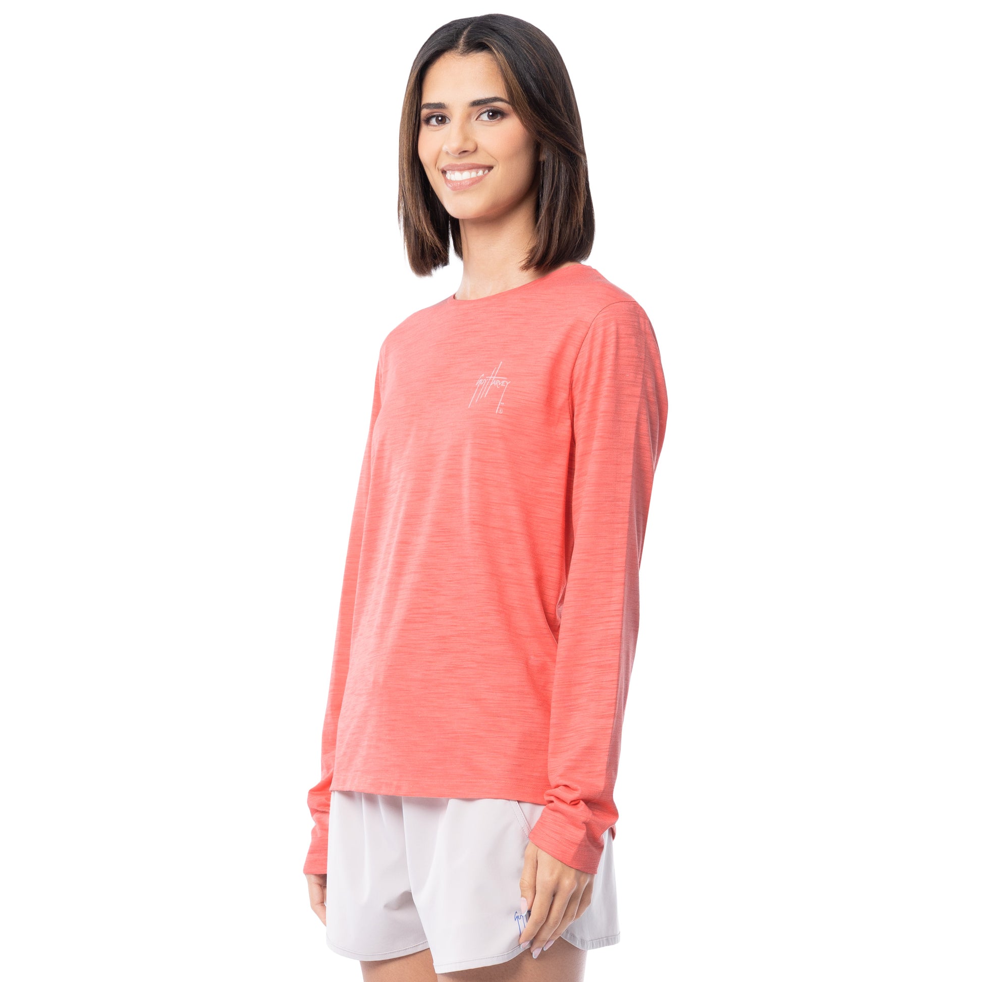 Woman wearing a coral long-sleeve shirt and white shorts on a white background