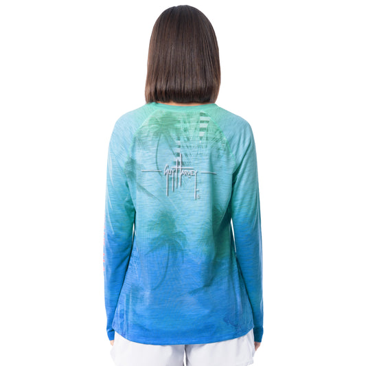 Woman wearing a blue and green tie-dye long-sleeve shirt with a logo on the back against a white background