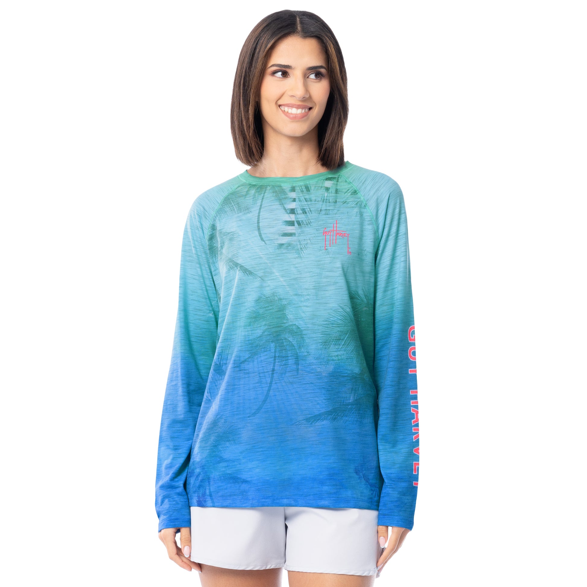 Woman wearing a blue and green gradient long-sleeve shirt with a red  Guy Harvey logo on a white background
