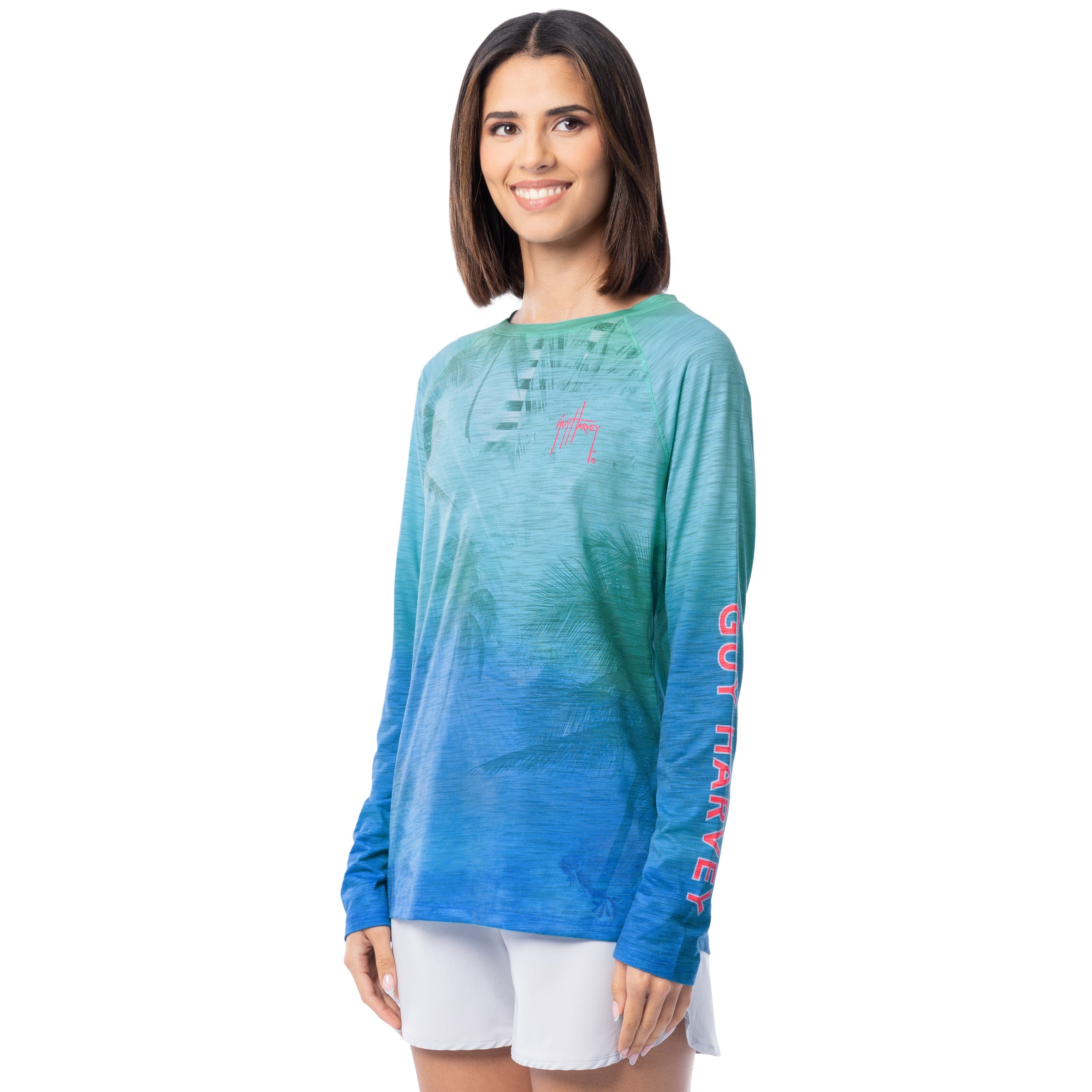Woman wearing a blue and green gradient long-sleeve shirt with 'Guy Harvey' text on sleeves against a white background
