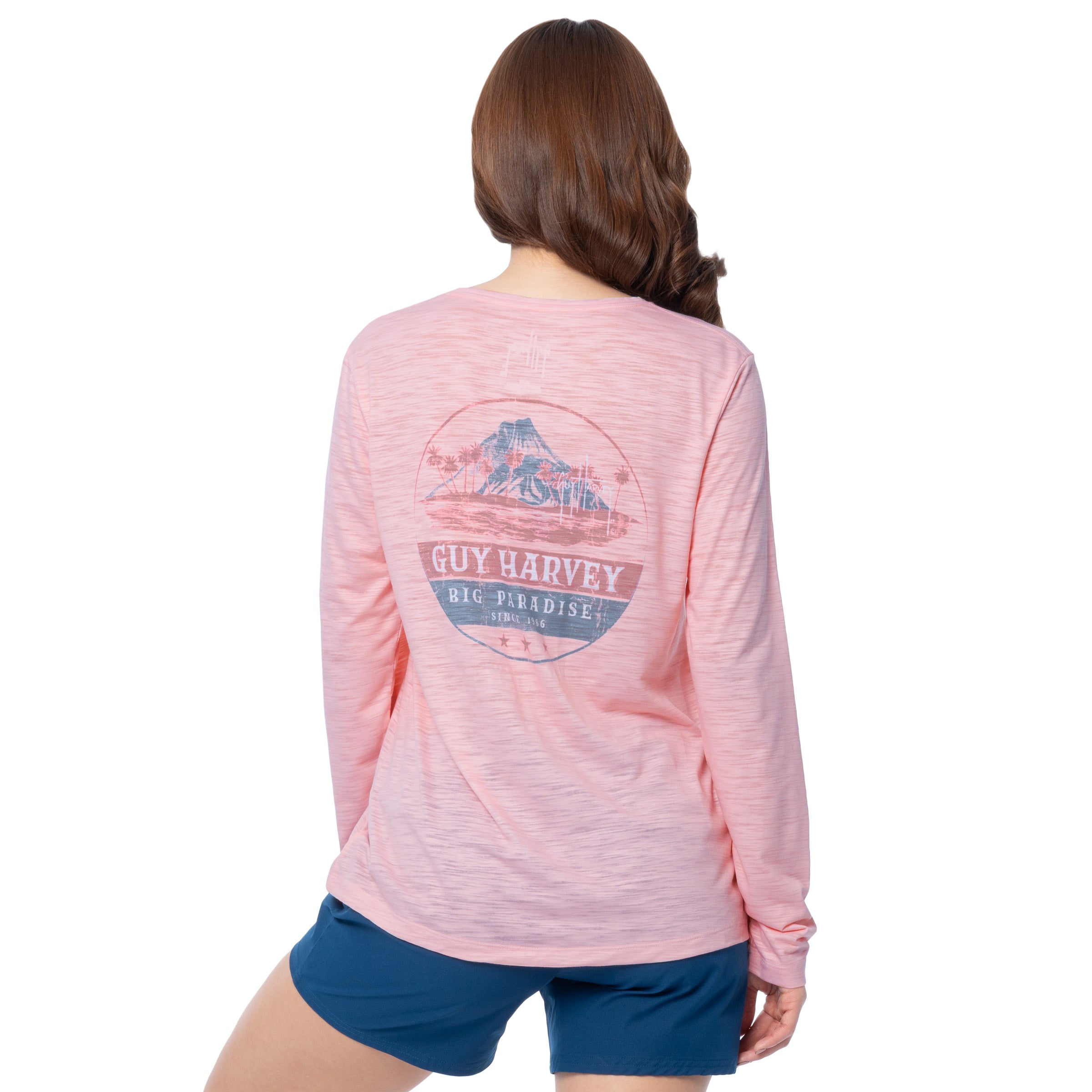 Person wearing a pink long-sleeve shirt with a Volcano paradise design on the back, standing against a white background.