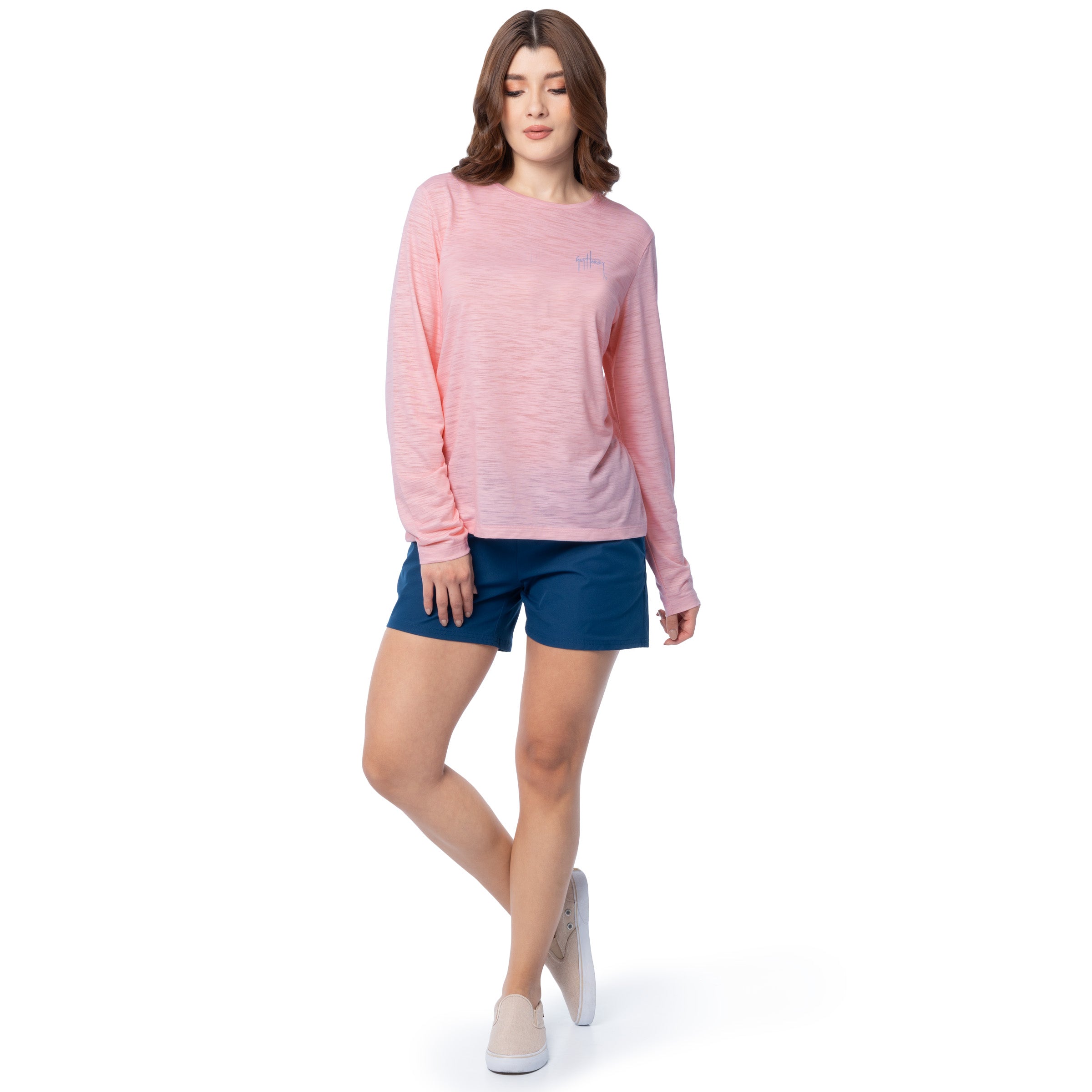 Woman wearing a pink long-sleeve shirt and blue shorts on a white background