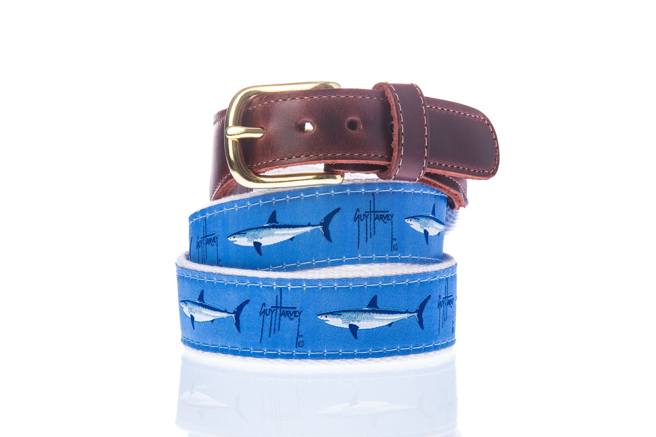 Guy Harvey Men’s Mako Leather Tab Belt with blue cotton webbing featuring mako shark illustrations, brown leather tabs, and brass buckle