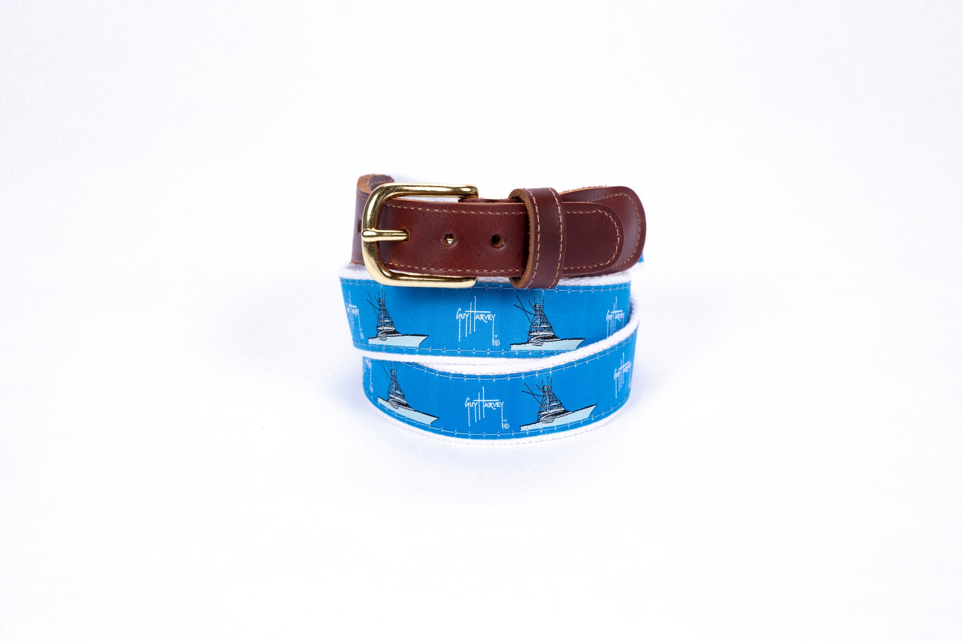 Guy Harvey Men’s Fishing Boat Leather Tab Belt with bright blue cotton webbing, illustrated offshore sportfishing boats, brown leather tabs, and brass buckle.