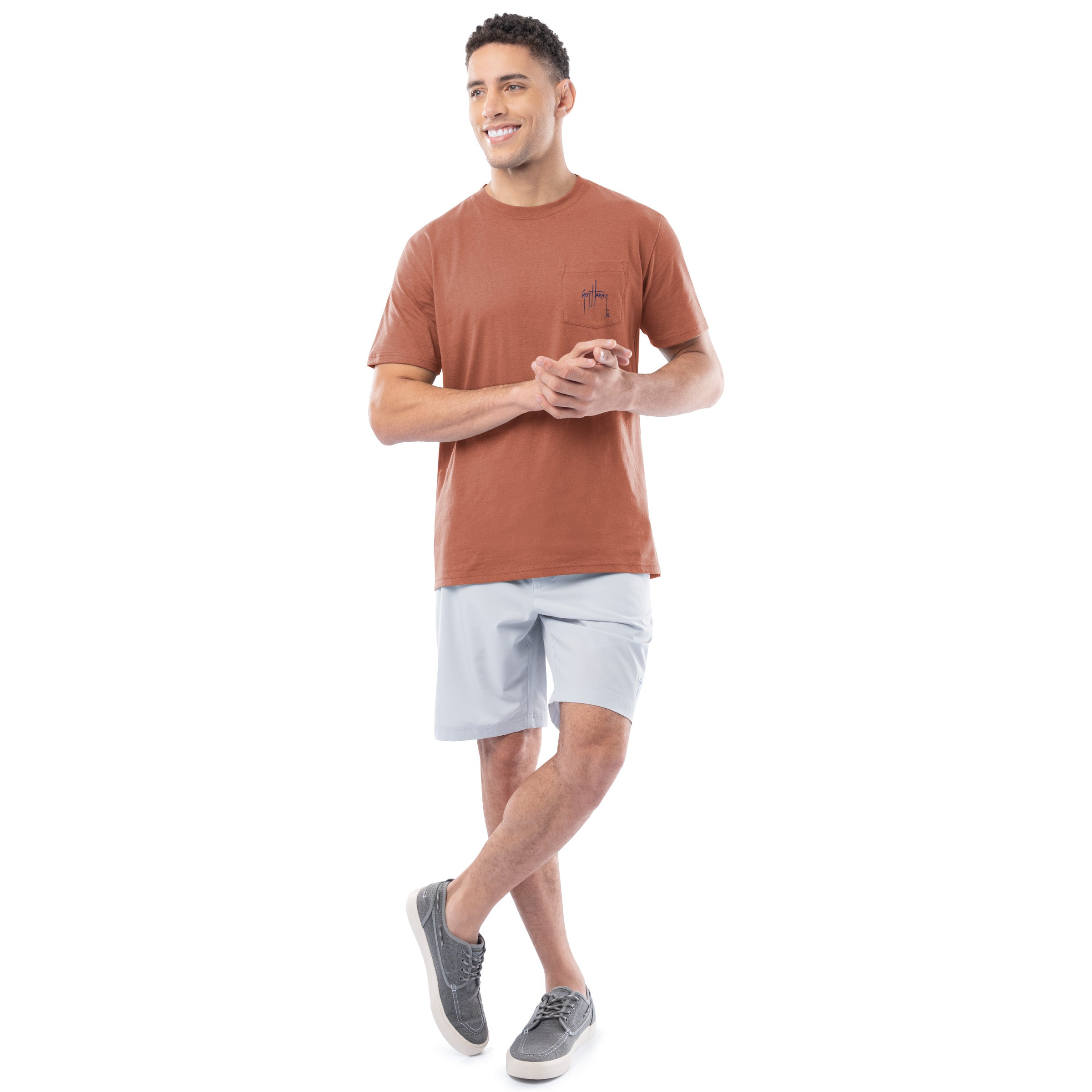 Man wearing a brown t-shirt and light gray shorts on a white background