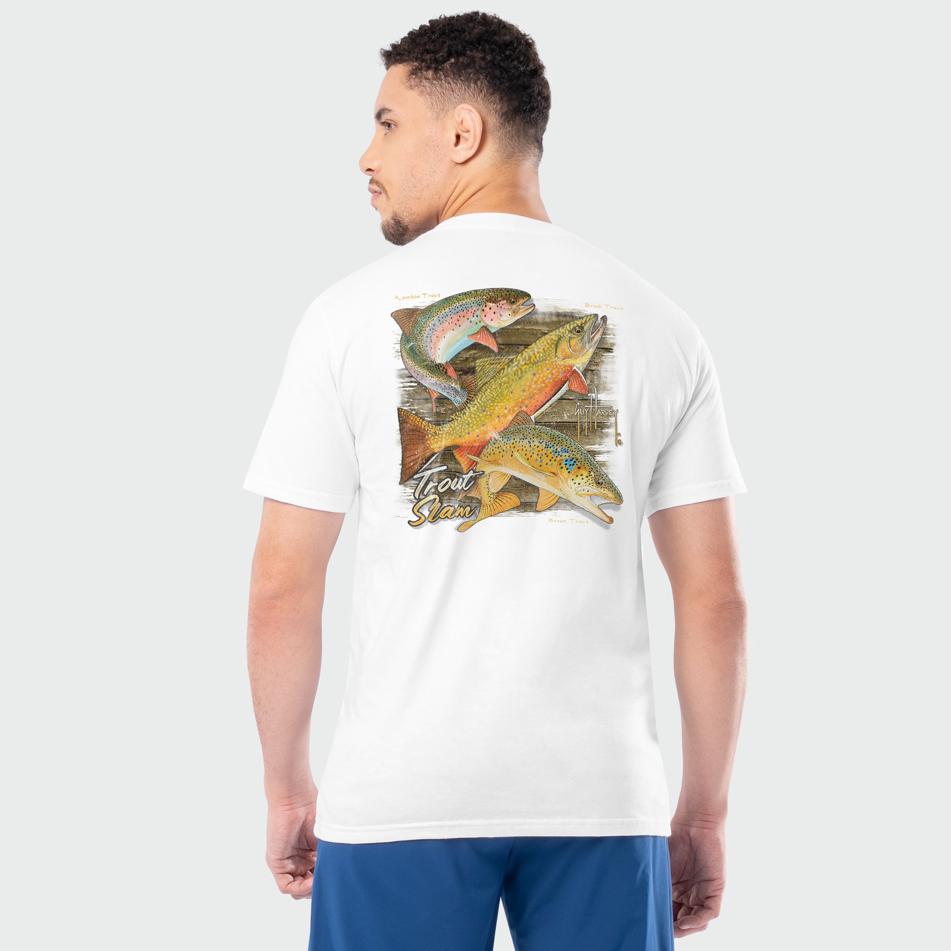 Man wearing a white t-shirt with a colorful trout fish design on the back against a light gray background