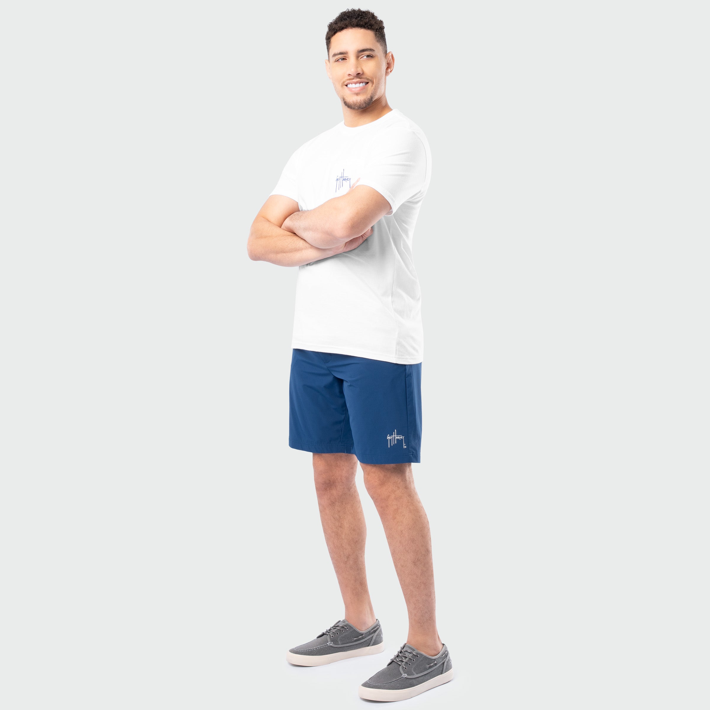 Man wearing a white t-shirt and blue shorts on a plain background