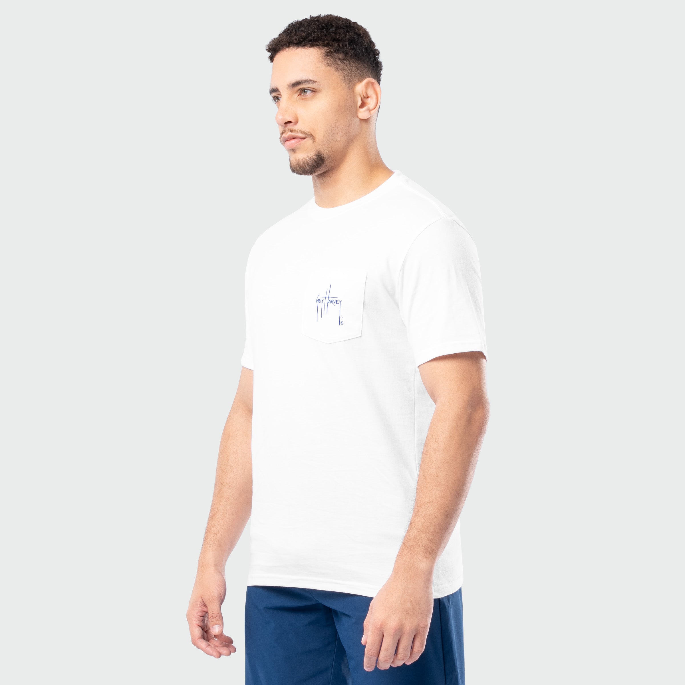 Man wearing a white t-shirt with a small logo on a plain background