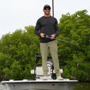 A man wearing an angler edge performance fishing pant from Guy Harvey, paired with a Marlin Air Long Sleeve Crew tee for sun protection while fishing on a boat.