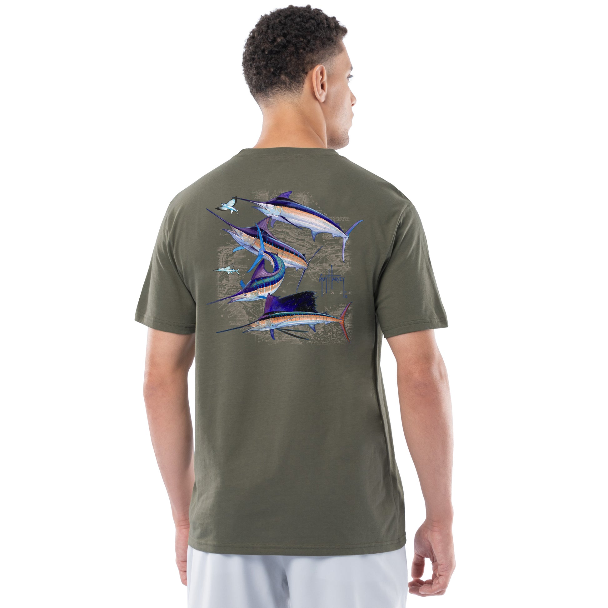 Man wearing a green t-shirt with fish illustrations on the back, standing against a white background