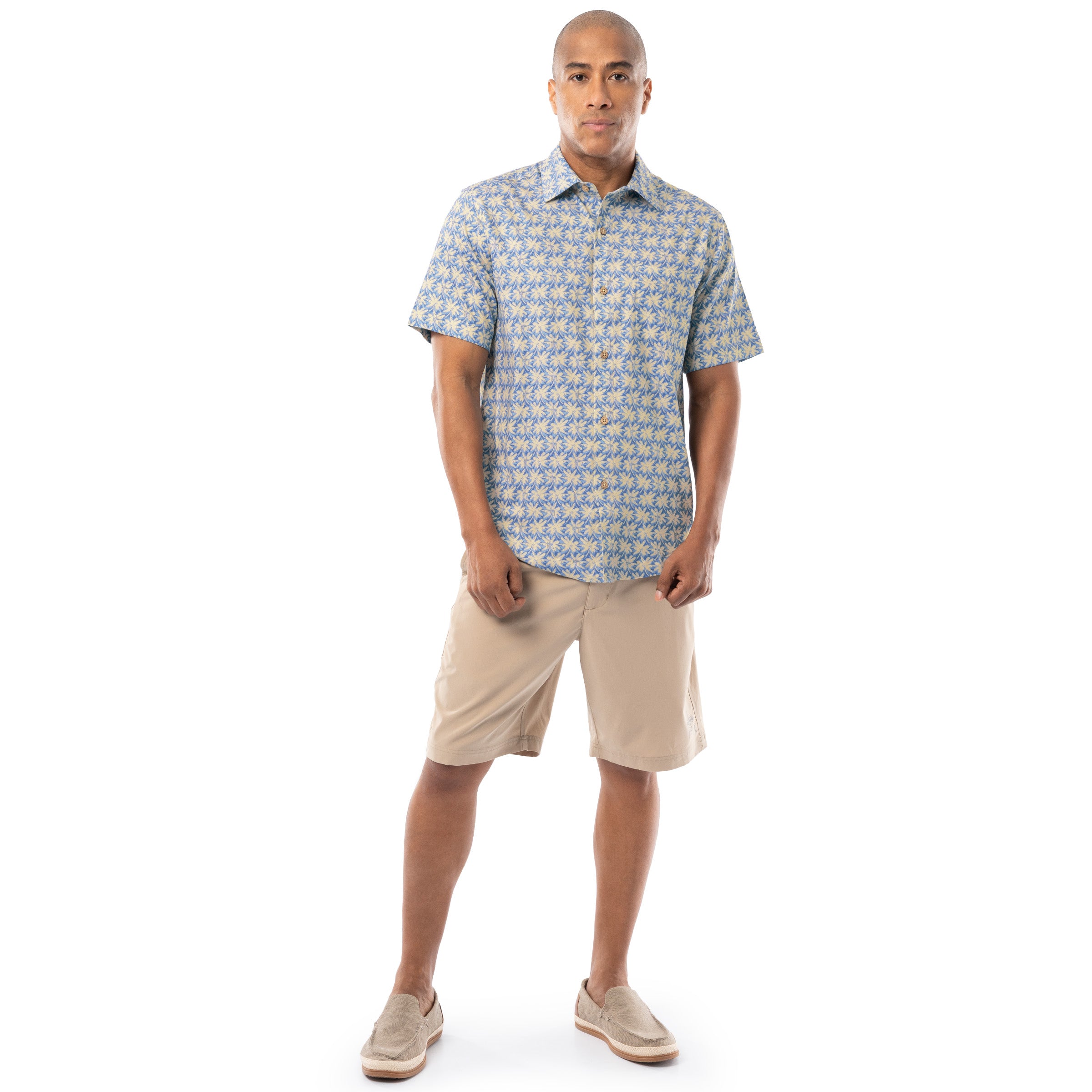 Lifestyle image of model wearing blue and sand Guy Harvey Men’s Dot Palm Resort Shirt with khaki shorts.