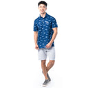 Lifestyle image of model wearing ocean blue Guy Harvey Men’s Double Vision Printed Performance Polo with gray shorts.