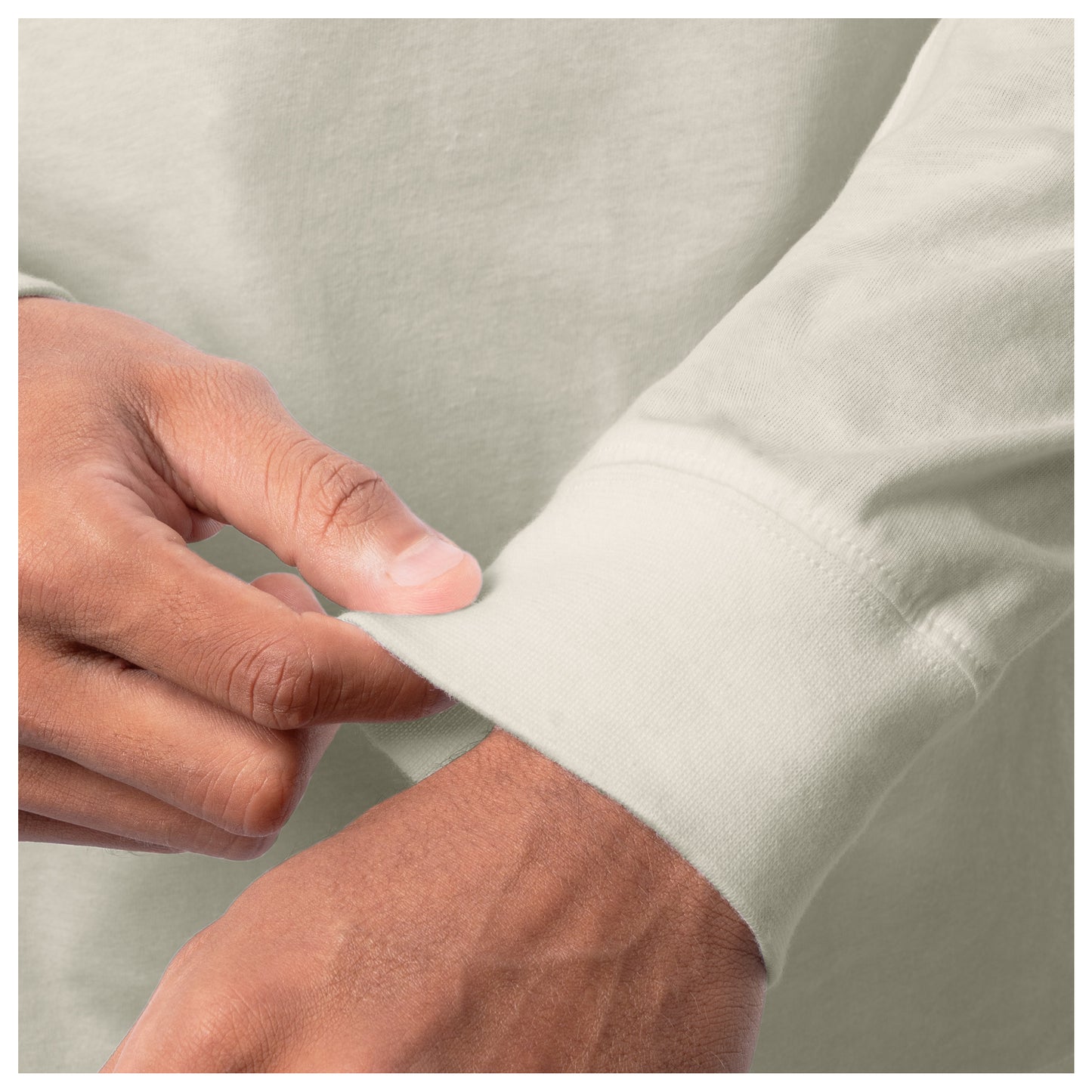 Close-up of a hand adjusting the cuff of a light-colored shirt against a neutral background