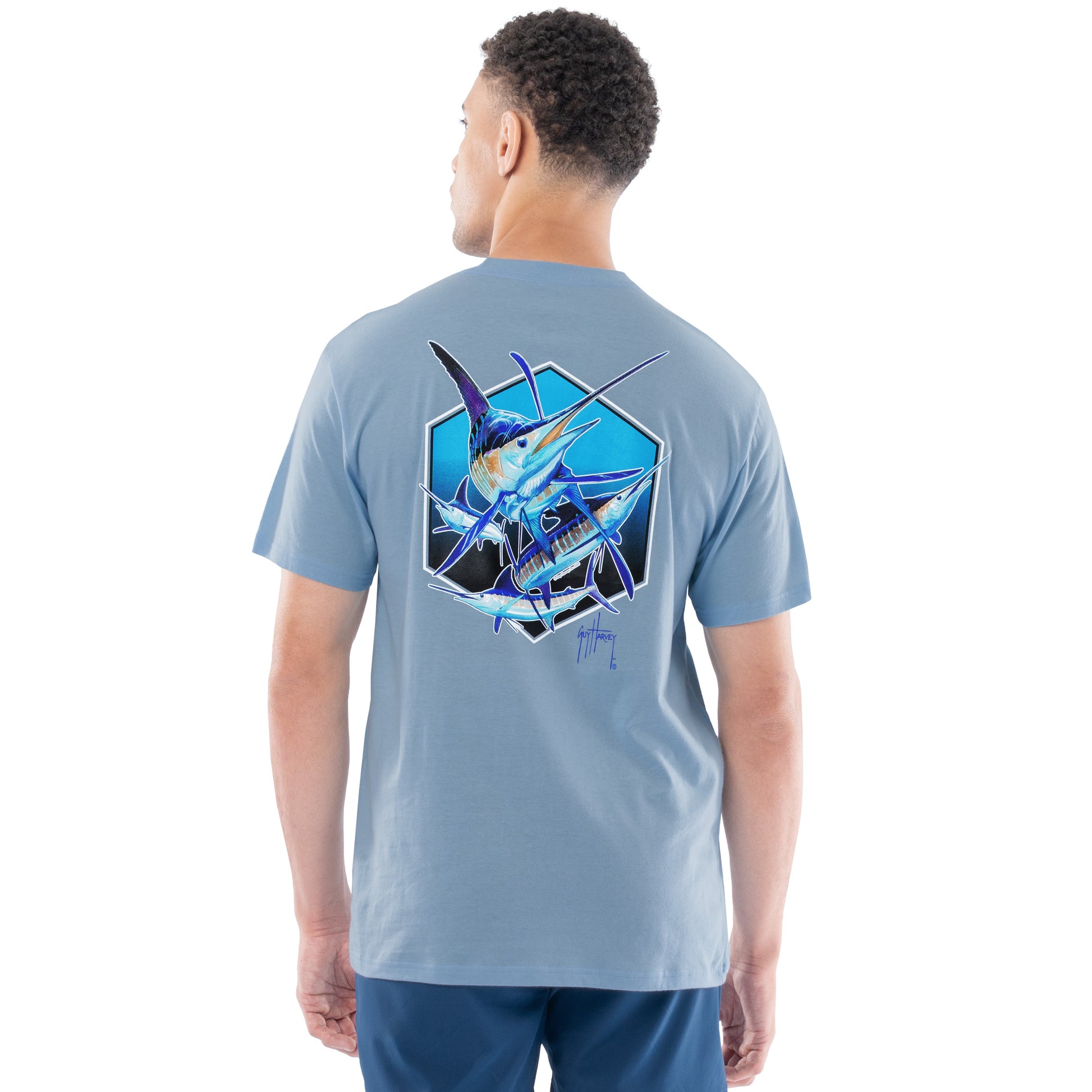 Man wearing a light blue t-shirt with a graphic design of a pack of marlins on the back, standing against a white background